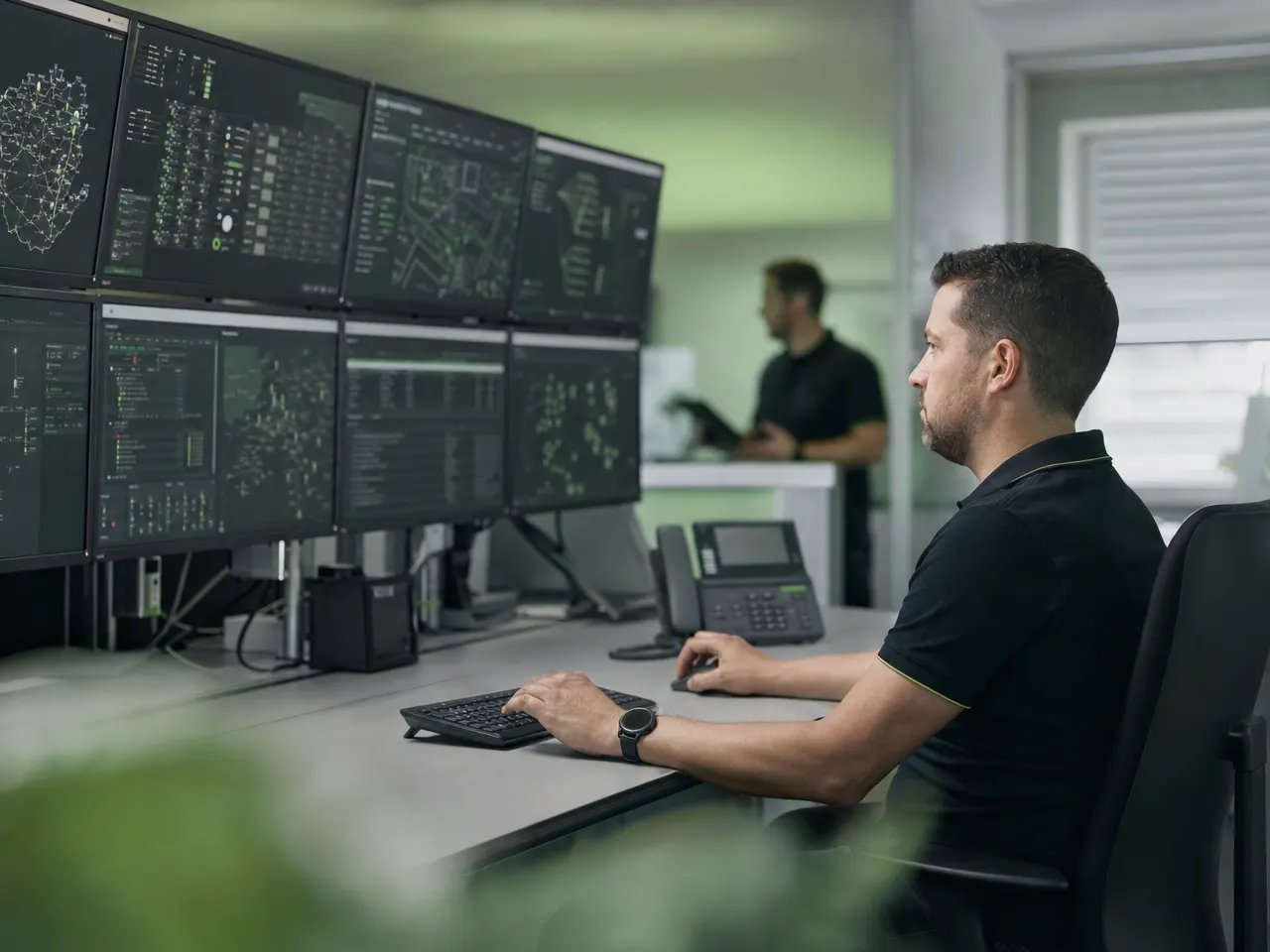 Monitorwand einer Leitwarte mit Netzwerktechnik und Systemanzeigen