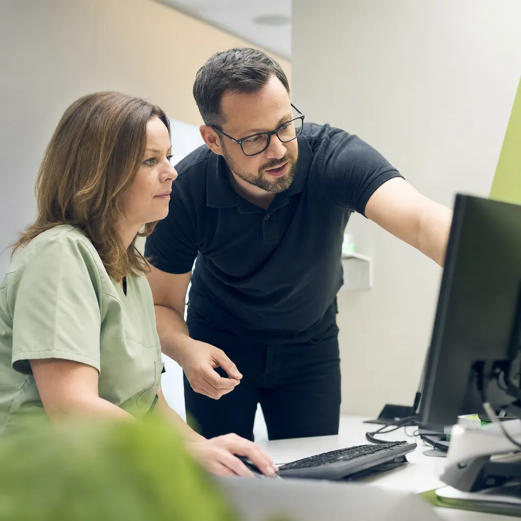 IT-Techniker unterstützt Praxispersonal an einem Arbeitsplatz