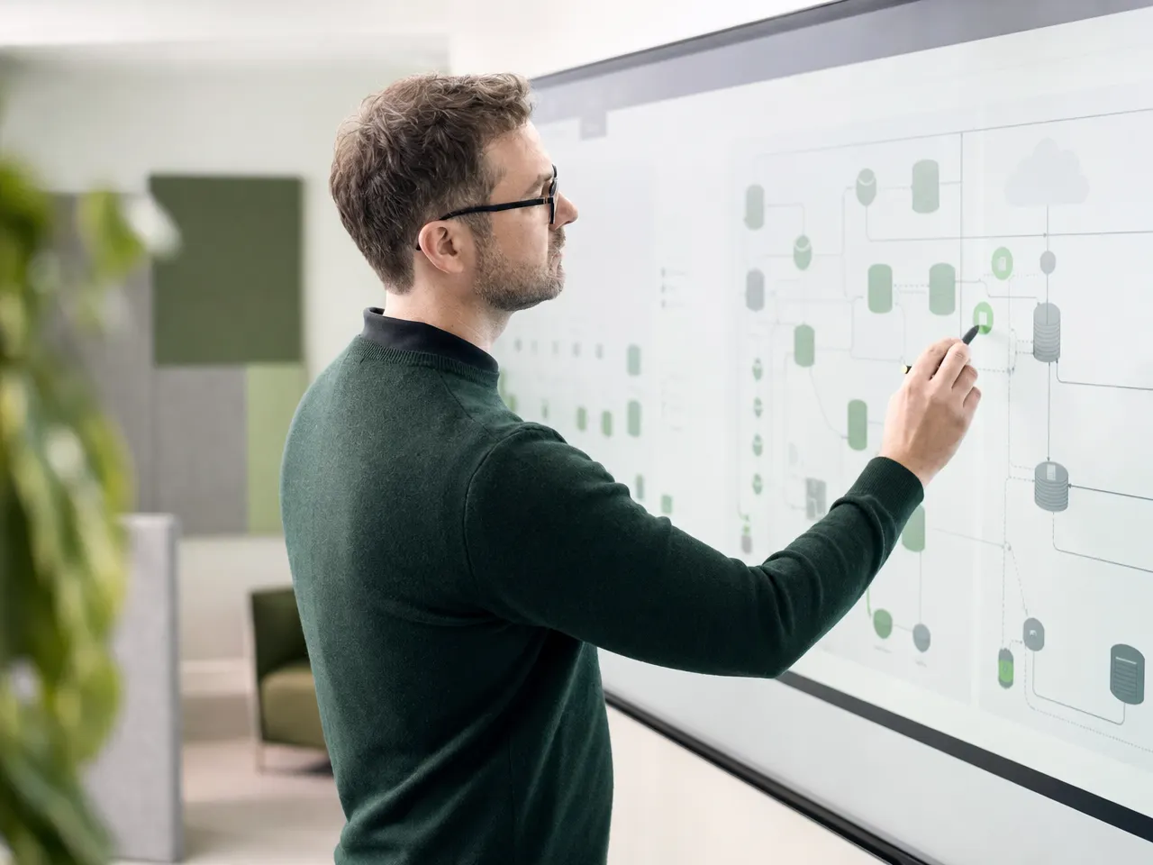 IT-Architekt plant eine Systemlandschaft an einem großen Bildschirm mit Diagrammen