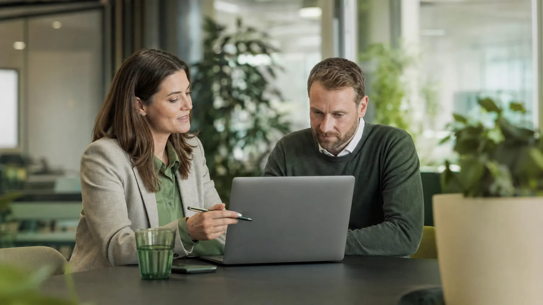 IT-Beraterin und Kunde besprechen einen Betriebsreport an einem Tisch