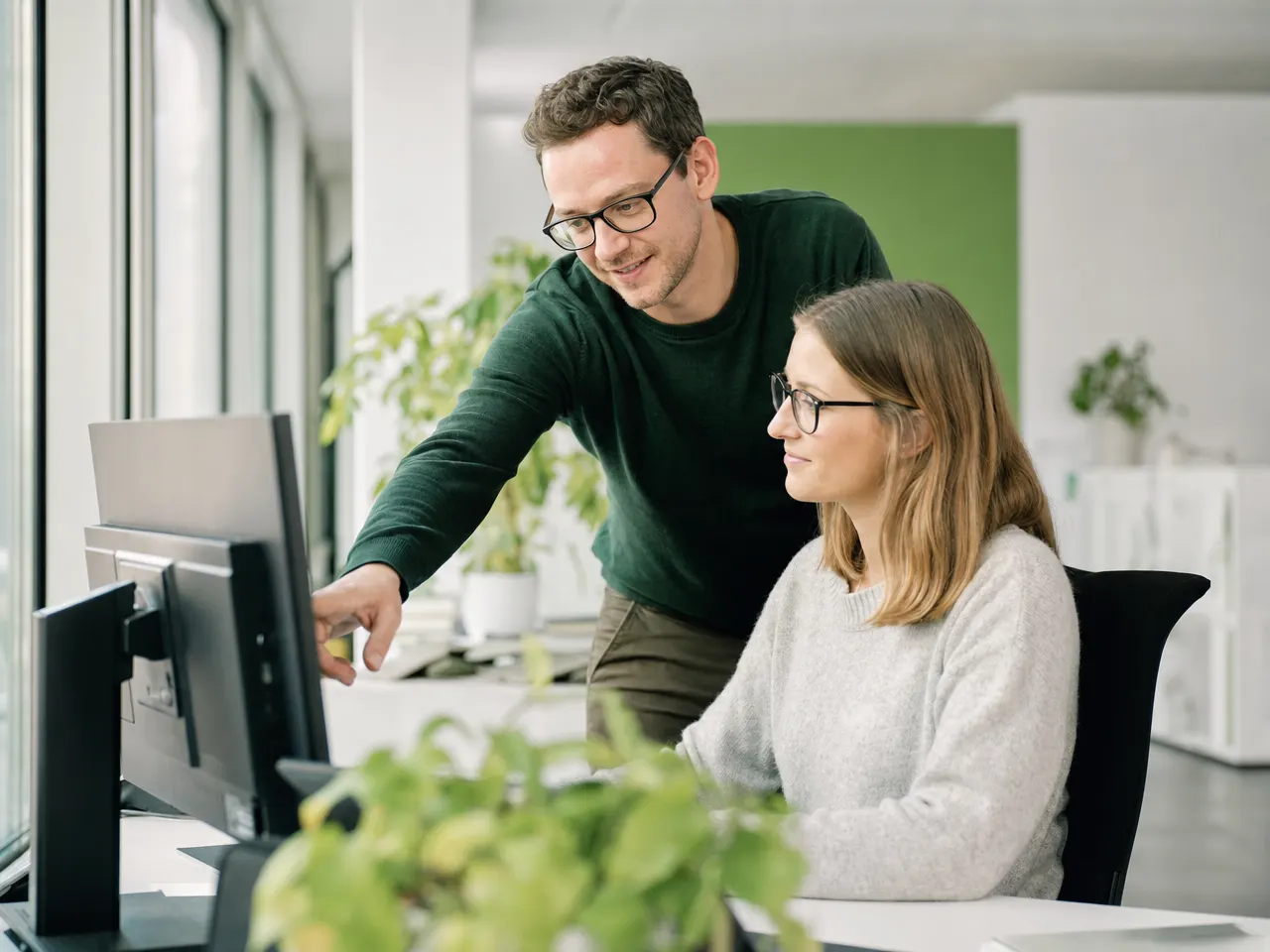 IT-Techniker unterstützt eine Mitarbeiterin an ihrem Arbeitsplatz im Büro