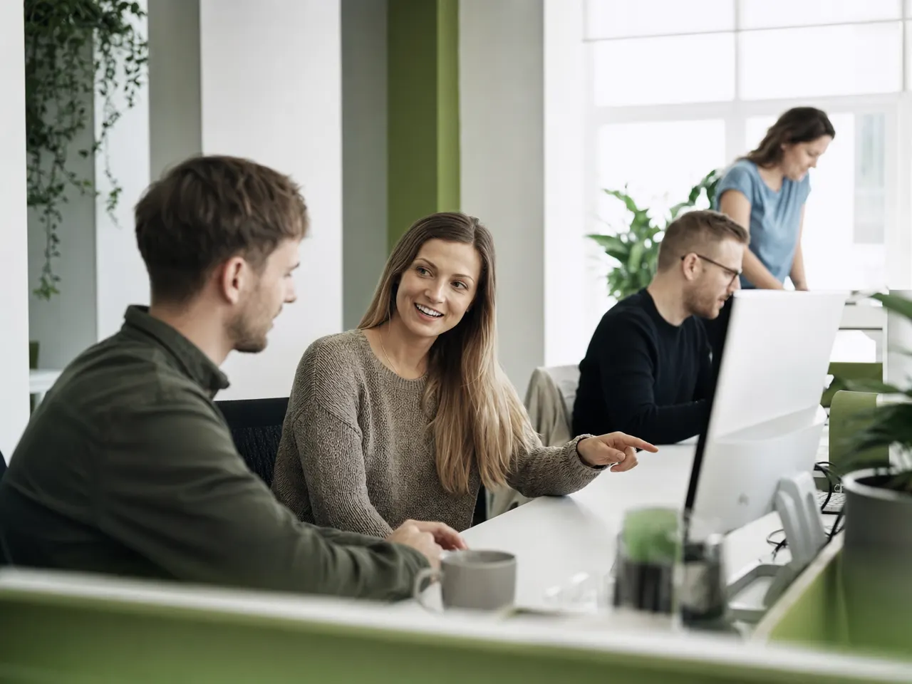 Zwei IT-Fachkräfte im Gespräch mit einer Kundin an einem Besprechungstisch
