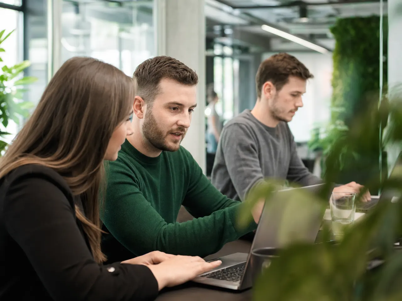 IT-Team arbeitet gemeinsam an Laptops in einem hellen Büro